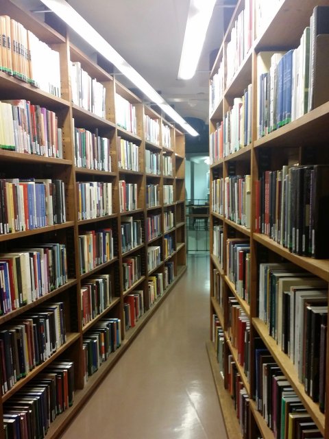 Looking down a narrow aisle between shelves at the National Library of Finland. Many hundreds of books are in view.